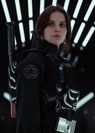 Photo of Felicity Jones as Jyn Erso from Rogue One: A Star Wars Story dressed in black Imperial outfit in a black corridor.